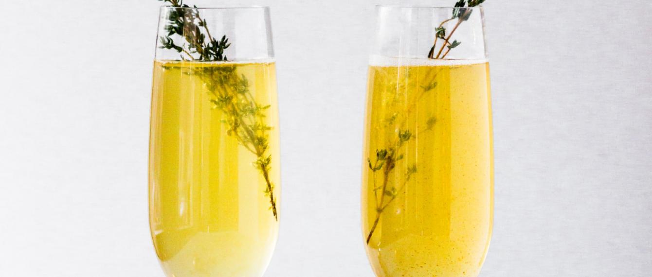 twee champagneglazen met drank en tijmtakje